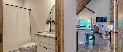 A bathroom with a toilet, shower curtain, and a vanity with a mirror.