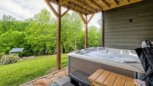 Un bain à remous installé sous une pergola en bois, offrant une vue sur un paysage verdoyant et luxuriant.