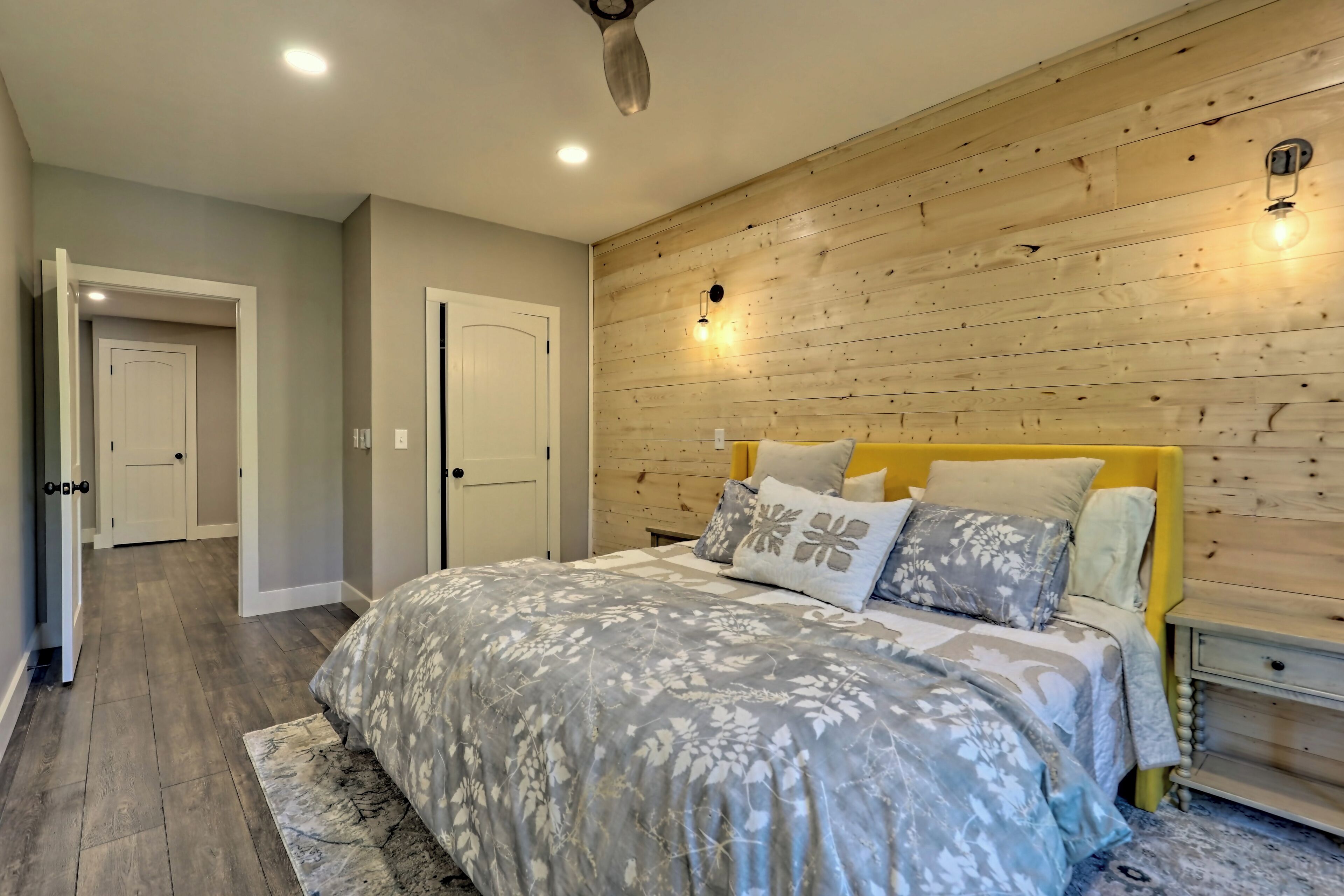 A bedroom with a wooden headboard, a bed with floral bedding, and a nightstand with a lamp.