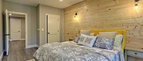 A bedroom with a wooden headboard, a bed with floral bedding, and a nightstand with a lamp.