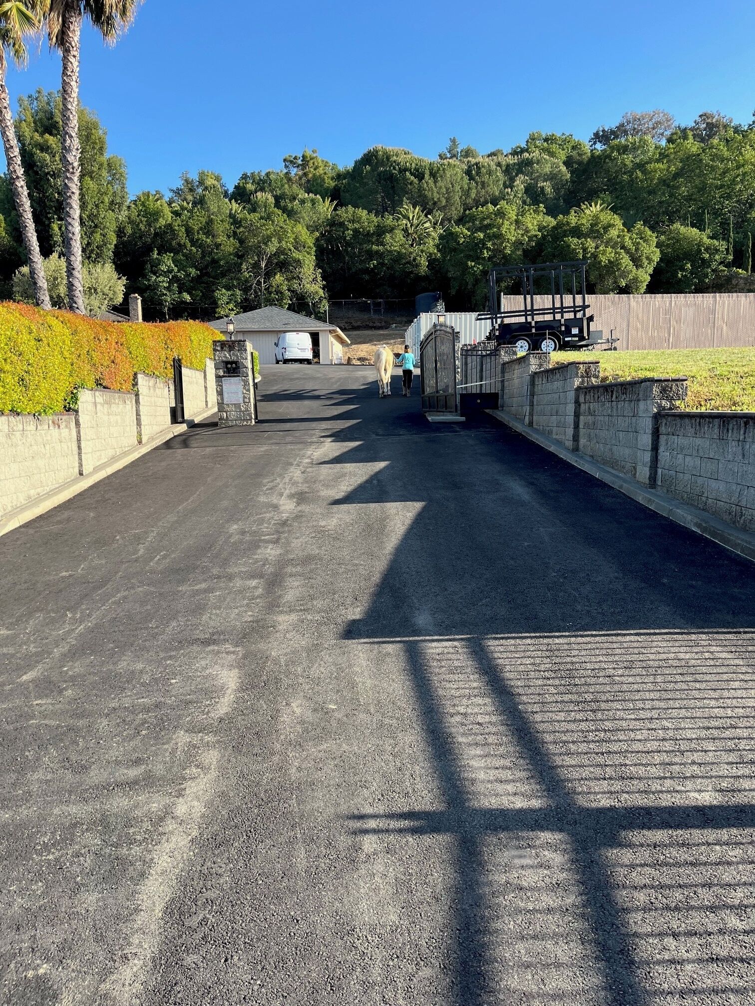 Un camino de adoquines conduce a una zona vallada donde se ve una camioneta blanca estacionada.