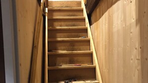 Una escalera de madera con barandilla que lleva a un rellano con almohadones.