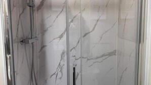 Box doccia in vetro con finitura in marmo.