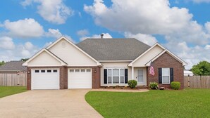 A two-story house with a garage, a brick section, and a well-maintained lawn.
