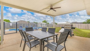 A covered patio with a pool, barbecue grill, and outdoor seating area.
