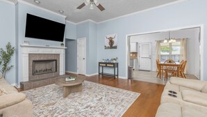 A living room with a fireplace, a television, and a dining area with a table and chairs.