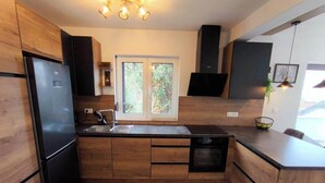 Een moderne keuken met houten kastjes, een inbouw vaatwasser en een groot raam dat voor natuurlijk licht zorgt.
