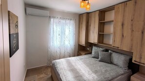 Een slaapkamer met een bed, een houten garderobe en een plafondlamp.