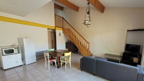 A spacious living area with a dining table, two chairs, a sofa, a staircase, a chandelier, and a television. - SPACIOUS GITE WITH GARAGE (Talairan)