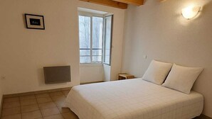 A bedroom with a large bed, a window, and a wooden ceiling. - SPACIOUS GITE WITH GARAGE (Talairan)