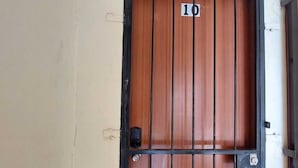 Une porte en bois, surmontée d’un portail en métal noir portant le numéro 10, et d’une petite fenêtre.
