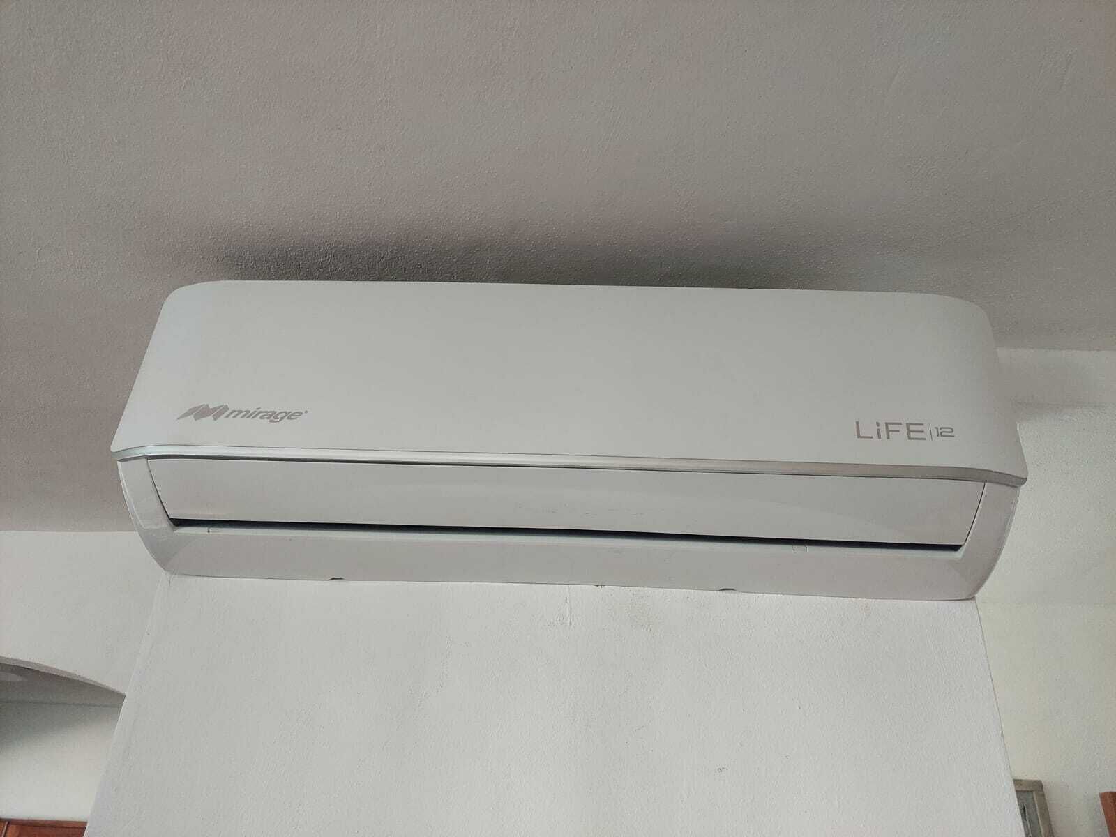 A white air conditioning unit labeled 'mirage' and 'LIFE12' mounted on a wall.