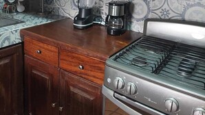 Une cuisine avec des meubles en bois, un four à micro-ondes, une machine à café et une cuisinière à gaz.