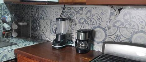 Une cuisine avec des meubles en bois, un four à micro-ondes, une machine à café et une cuisinière à gaz.