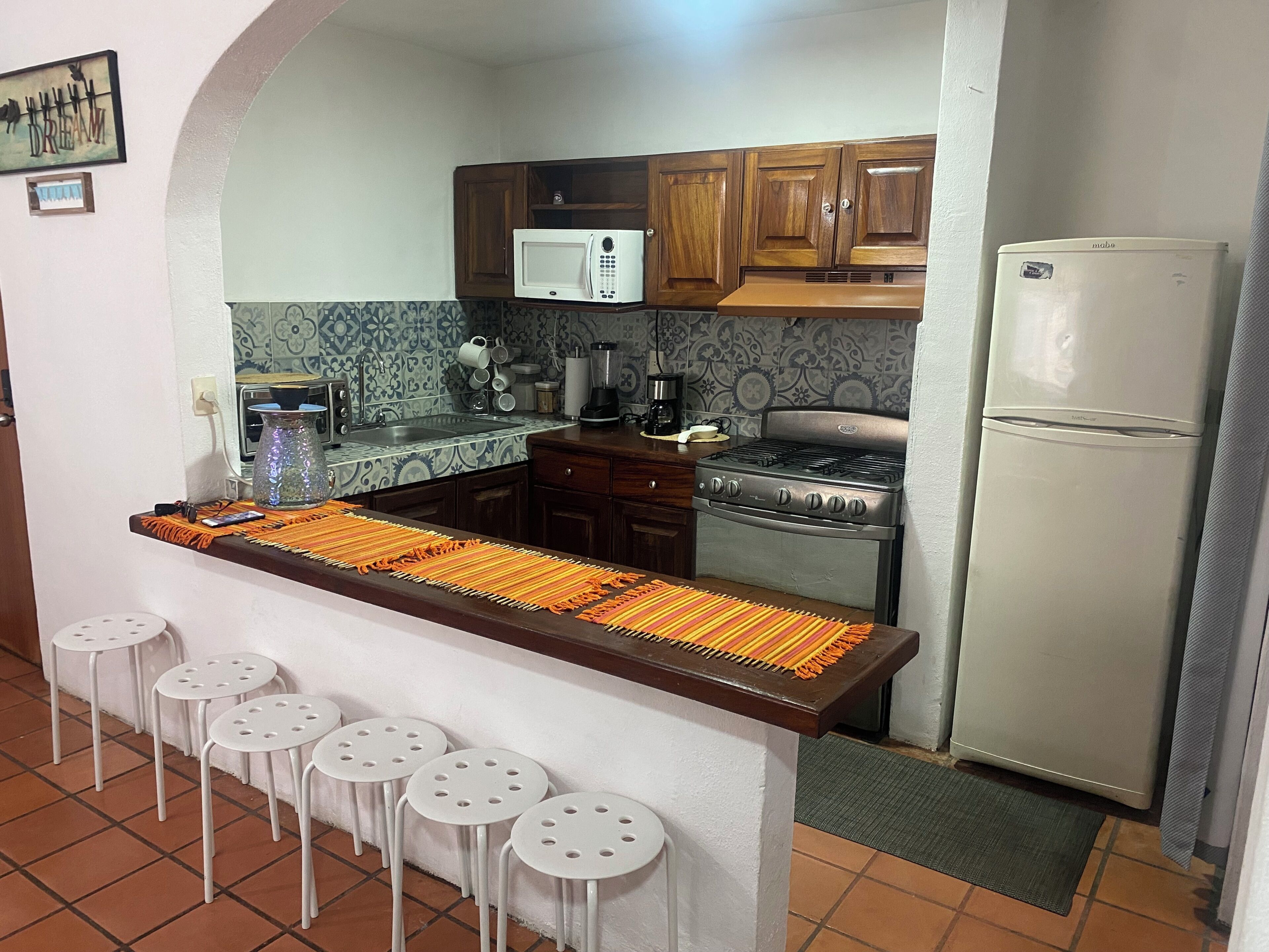 A kitchen with a central island, a stove, a microwave, and a refrigerator.