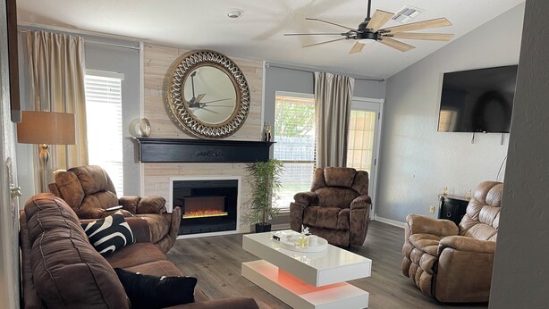 A modern living room with a fireplace, leather sofas, a coffee table, and a ceiling fan. - Relaxation, Comfort & Style (Lawton)