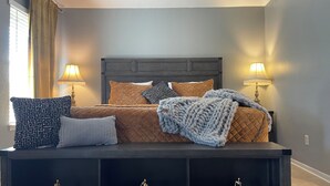 A neatly made bed with a quilted headboard, two bedside lamps, and a bedside table with a lamp. - Relaxation, Comfort & Style (Lawton)