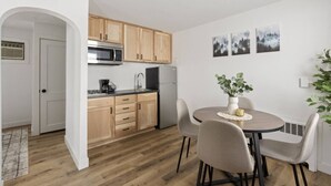 A compact kitchen with wooden cabinets, a stainless steel microwave, and a black refrigerator. There is a dining area with a round table and four chairs. - Across from Leech Lake! (Walker)
