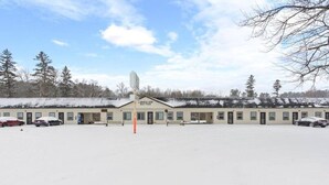 A motel with multiple rooms, a central sign, and a snow-covered parking lot. - Across from Leech Lake! (Walker)