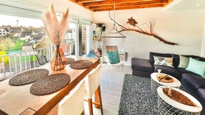 Una sala de estar moderna con techo de madera, un sofá, una mesa de centro y vistas al exterior.