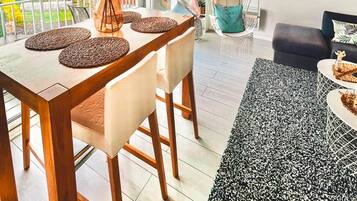 Uma sala de jantar com mesa e cadeiras de madeira, uma cadeira suspensa e um sofá.