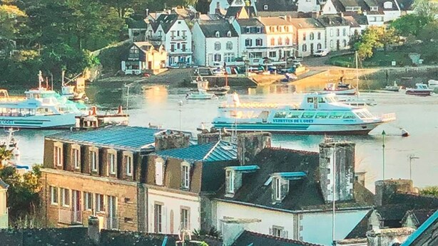 Un pueblo costero con casas tradicionales, un puerto deportivo y barcos.