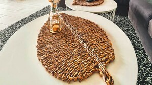 Una sala de estar acogedora con un sillón colgante, un sofá y una mesa de centro con posavasos tejidos.