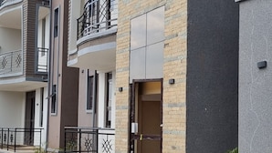 A multi-story residential building with balconies, a tiled entrance, and a brick facade. - Abba nest, Enjoy a home away from home (Kampala)