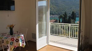 Une pièce avec un balcon, une table recouverte d’une nappe à motifs floraux et un vase rempli de fleurs.