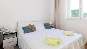 Un lit bien fait, avec des oreillers, une table de chevet avec une lampe et une fenêtre avec des rideaux.