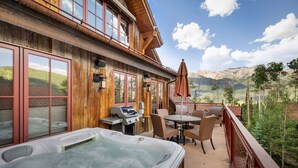 A wooden building with a hot tub, outdoor seating, and a view of mountains. - The Veranda at Trails Edge - penthouse views! (Mountain Village)