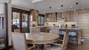 A modern kitchen with wooden cabinets, a round dining table, and bar stools. - The Veranda at Trails Edge - penthouse views! (Mountain Village)