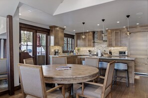 A modern kitchen with wooden cabinets, a round dining table, and bar stools. - The Veranda at Trails Edge - penthouse views! (Mountain Village)