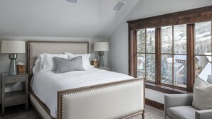 A bedroom with a large bed, two bedside tables with lamps, a window with a view of a snowy landscape, and a chair. - The Veranda at Trails Edge - penthouse views! (Mountain Village)