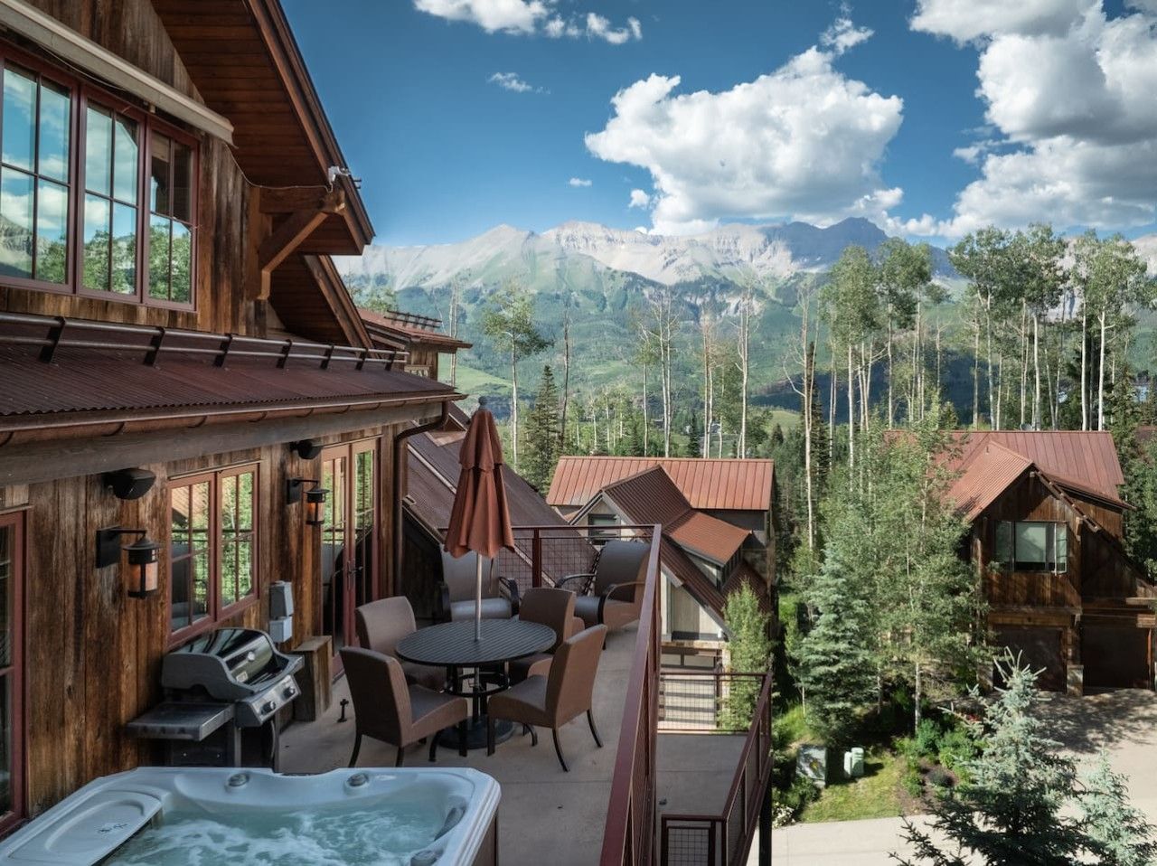 A wooden cabin with a hot tub, outdoor seating, and a mountain view.