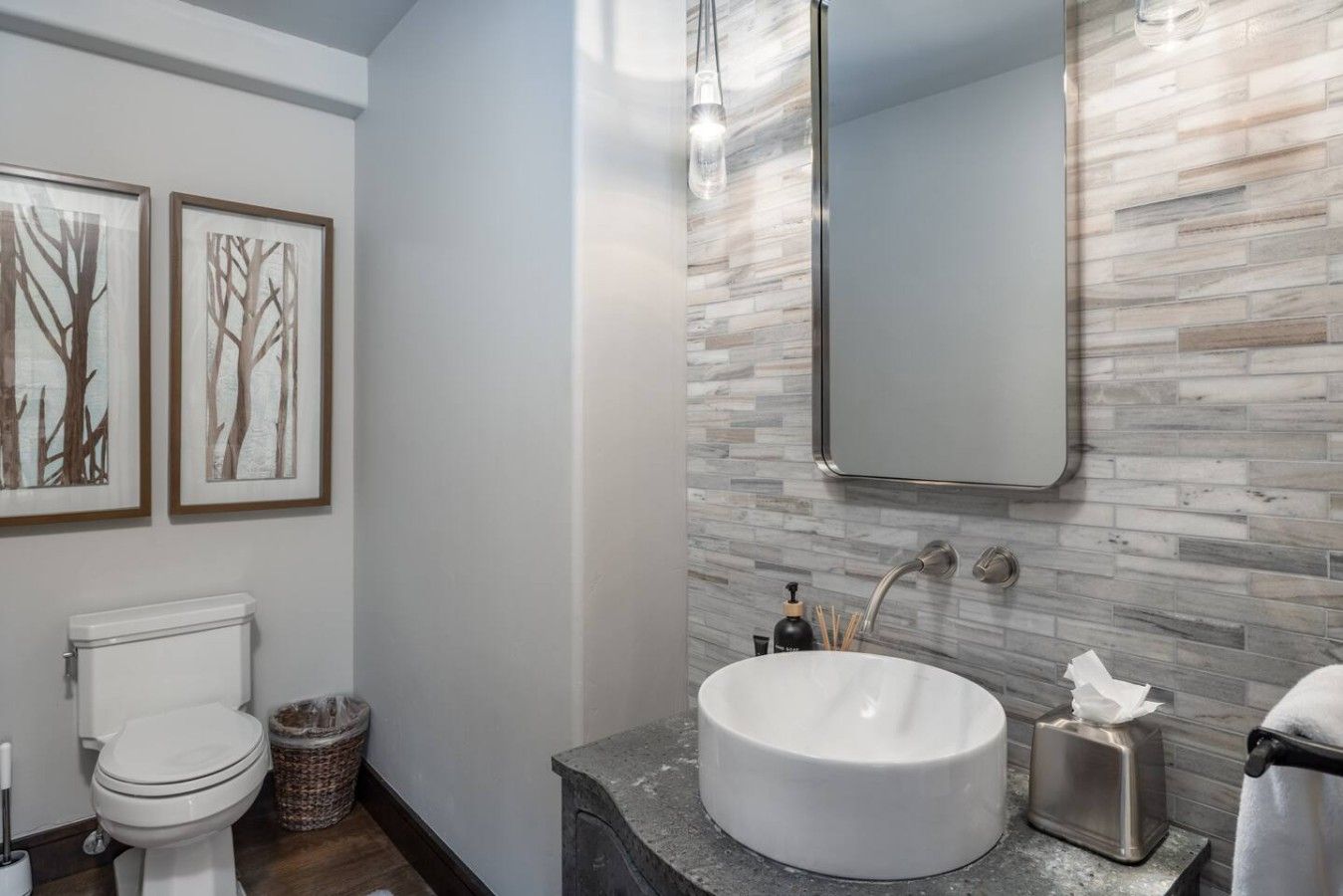 A modern bathroom with a white sink, a mirror, and two framed pictures on the wall.