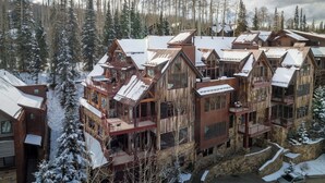 A multi-story wooden lodge with balconies and large windows, surrounded by a snowy forest. - The Veranda at Trails Edge - penthouse views! (Mountain Village)