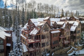 A multi-story wooden lodge with balconies and large windows, surrounded by a snowy forest. - The Veranda at Trails Edge - penthouse views! (Mountain Village)