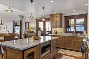 A modern kitchen with wooden cabinets, granite countertops, and pendant lighting. - The Veranda at Trails Edge - penthouse views! (Mountain Village)