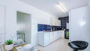 Une cuisine moderne avec des meubles blancs, un pare-feu bleu et un aménagement compact.