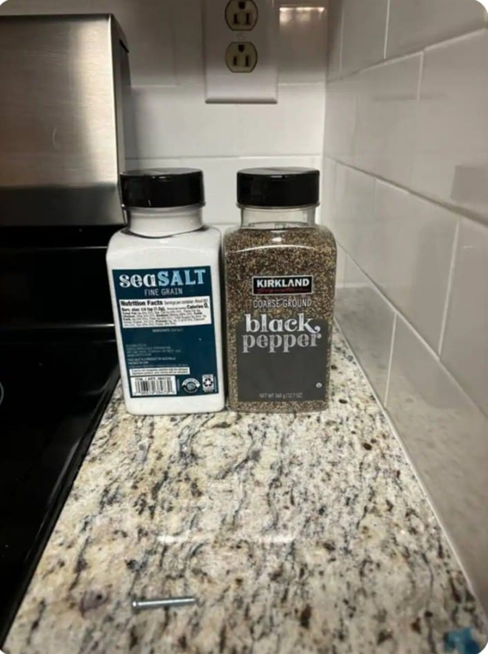 Two bottles of seasoning, one labeled 'Seasalt Fine Grain' and the other 'Kirkland Black Pepper', on a granite countertop.