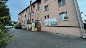 A multi-story building with a flag, a poster, and a parked car. - Ayyıldız Hostel (Belgrade)