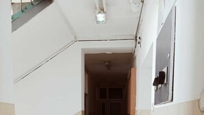 A narrow hallway with a tiled floor, a staircase on the left, and a door at the end. - Ayyıldız Hostel (Belgrade)