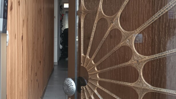 Un couloir en bois avec une porte en verre décorative ornée de motifs complexes.