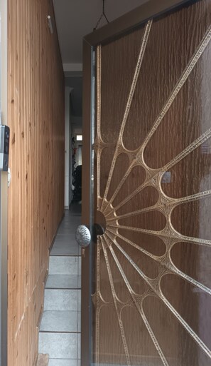 A wooden hallway with a decorative glass door featuring intricate patterns.
