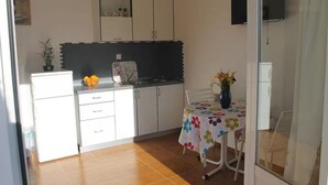 A compact kitchen with white cabinets, a black backsplash, and a small dining area with a floral tablecloth. - Charming 2-bedroom apartment with AC, WiFi in lovely Zaton (Zaton)