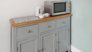 A kitchenette with a microwave, kettle, and a coffee cup on a wooden countertop. - 1 bedroom accommodation in Walcott (Walcott)