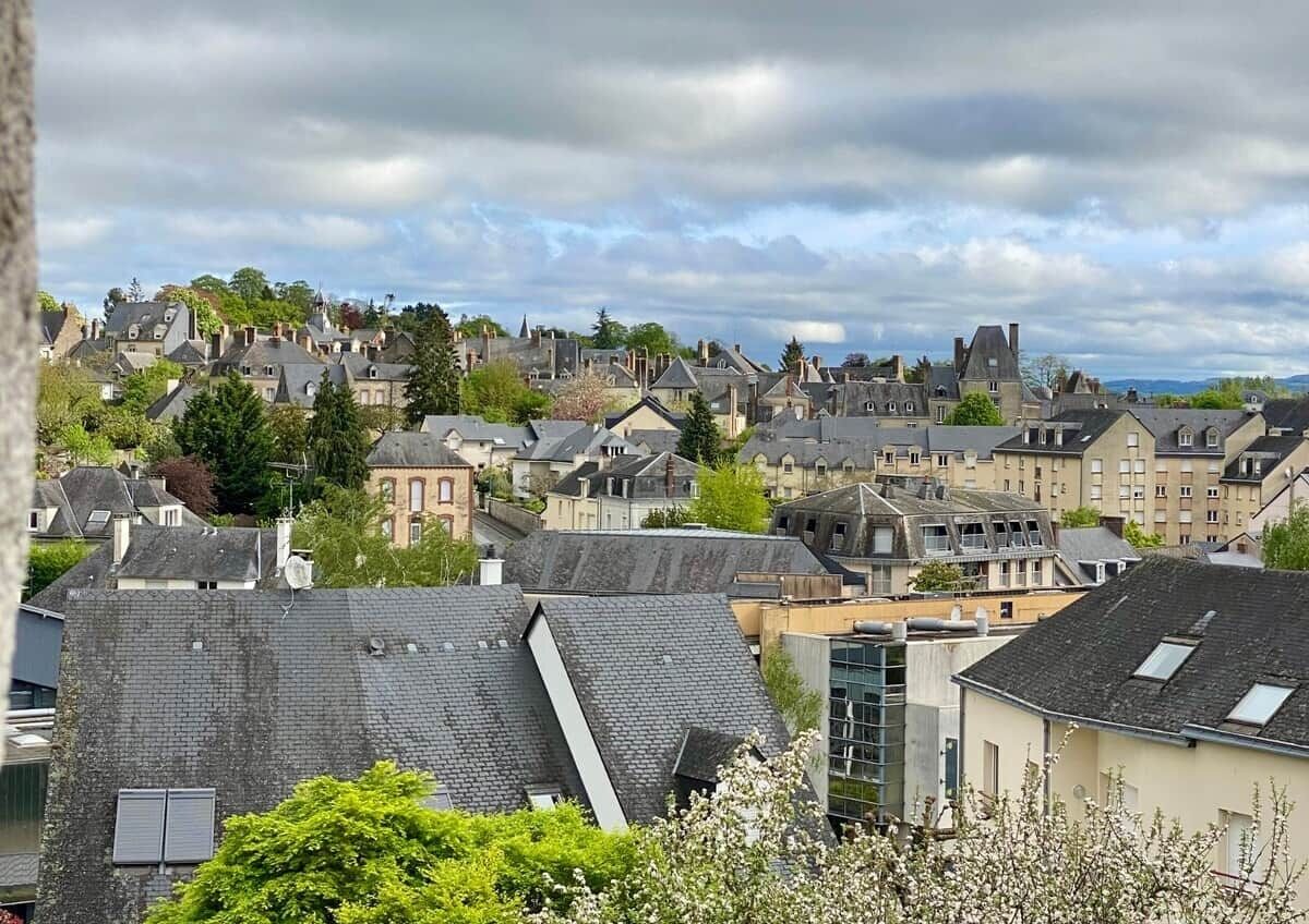 A residential area with multiple houses and buildings, some with sloped roofs and others with flat roofs.