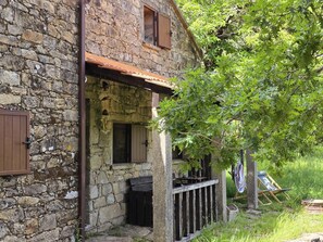 Un bâtiment en pierre avec une porte en bois, une fenêtre et un petit porche.