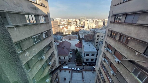 A view from a high-rise building looking down at a street with buildings and parked cars. - Vasile Apartment studio  (Bucharest)